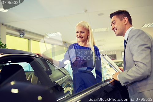 Image of happy woman with car dealer in auto show or salon