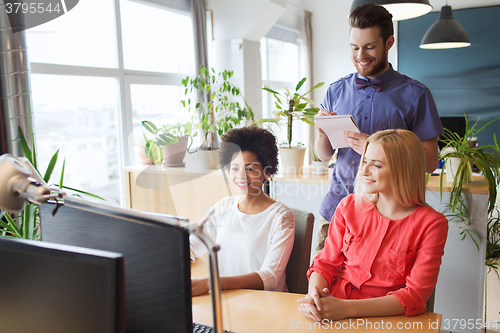 Image of happy creative team with computer in office