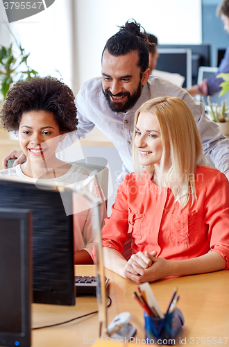 Image of happy creative team with computer in office