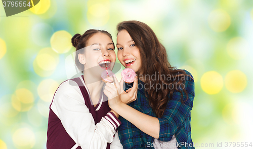 Image of happy pretty teenage girls eating donuts