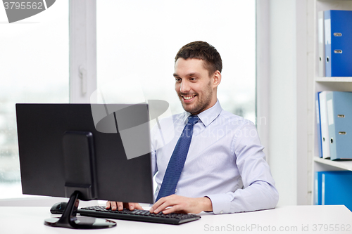 Image of smiling young businessman with computer at office