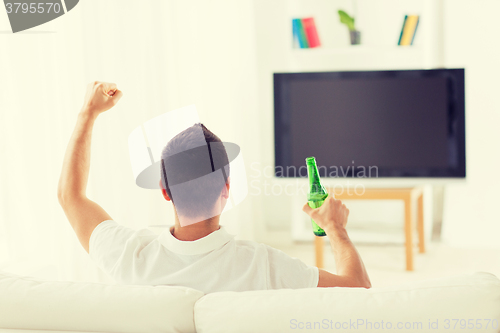 Image of man watching tv and drinking beer at home