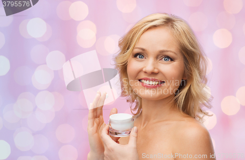 Image of happy woman applying cream to her face