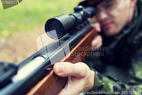 Image of close up of soldier or hunter with gun in forest