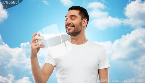 Image of smiling man with male perfume over blue sky