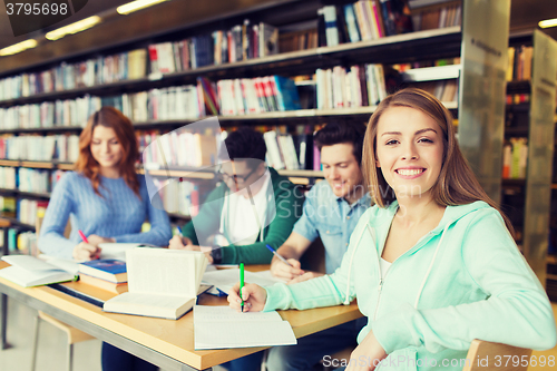 Image of happy student girl writing to notebook in library