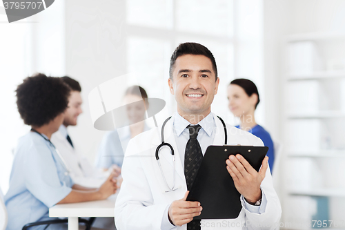 Image of happy doctor with clipboard over medical team