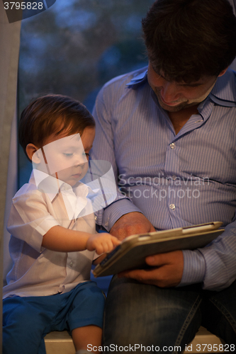 Image of Man and little boy playing with tablet