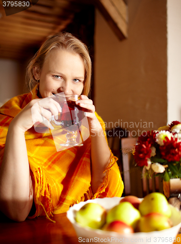 Image of Young woman is drinking tea and smiling.