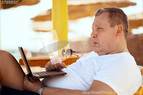 Image of Man relaxing with a laptop at beach resort