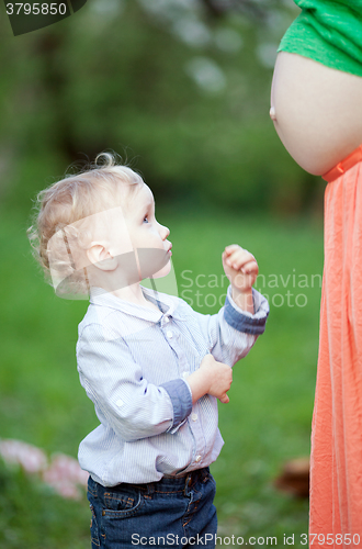 Image of Cute little boy looking at pregnant moms belly