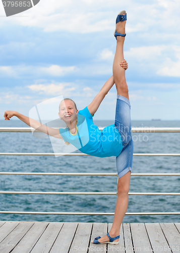 Image of Smiling girl making stretching exercise by the sea