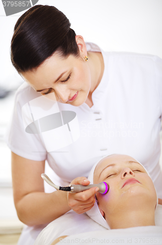 Image of Cosmetician providing lifting procedure with special equipment