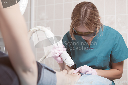 Image of Female cosmetician doing foot therapy using laser