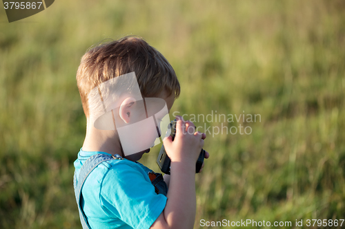 Image of Little boy with camera outdoor