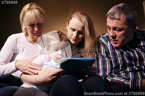 Image of Family watching boy playing game on touchpad