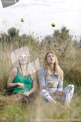 Image of Two playful girls juggling outdoors