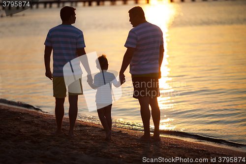 Image of Three male generations by the sea at sunset