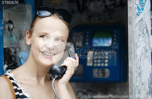 Image of Attractive woman using a public telephone