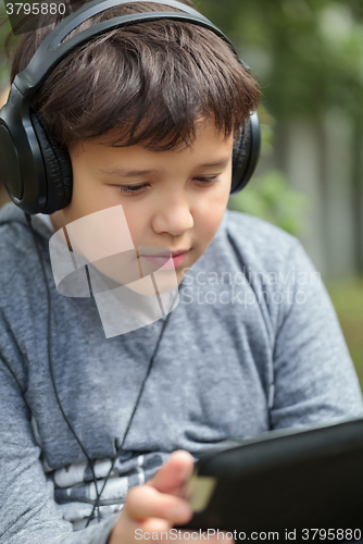 Image of Teenager in headphones using pad outdoor