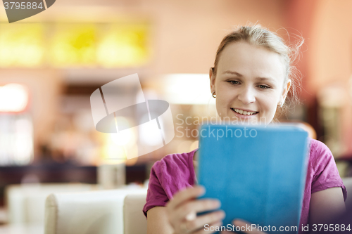 Image of Young happy woman in cafe with tablet PC