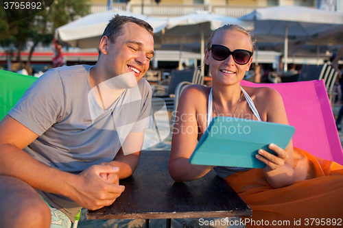 Image of Man and woman with pad on the beach