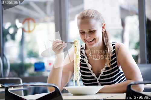 Image of Young woman eating spaghetti