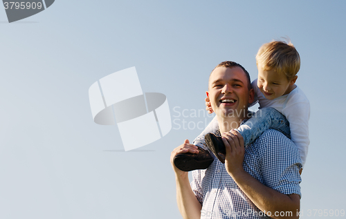 Image of Young father giving his son a piggy back ride