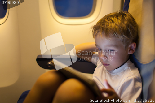 Image of Boy sitting in the plane and using tablet PC