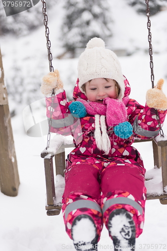 Image of little girl at snowy winter day swing in park