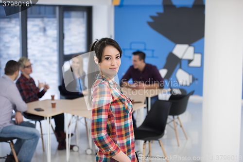 Image of portrait of young business woman at office with team in backgrou