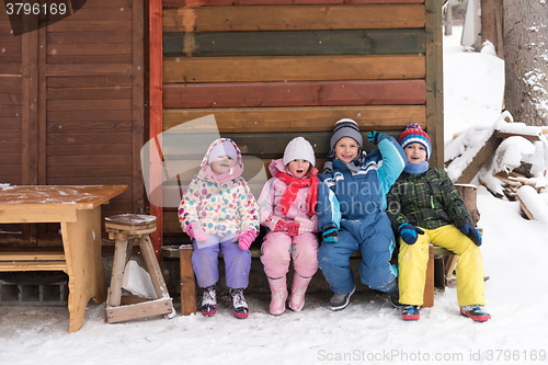 Image of little children group sitting  together  in front of wooden cabi