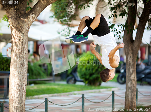 Image of Young sportsman doing front flip in the street