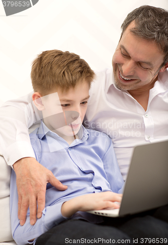 Image of Father watching son working with laptop