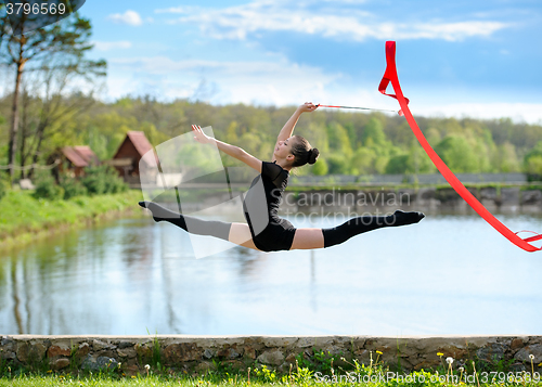 Image of Rhythmic gymnast girl exercising with ribbon outdoor