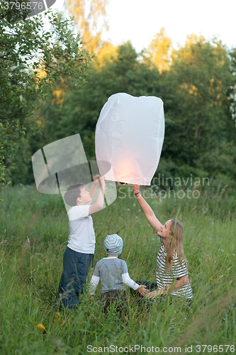 Image of Family of three flying paper lantern outdoor