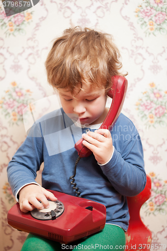 Image of Small boy talking on a red telephone