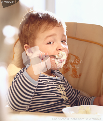 Image of Two year old boy eats porridge in the morning.