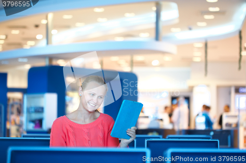 Image of Woman sitting in a waiting room reading tablet