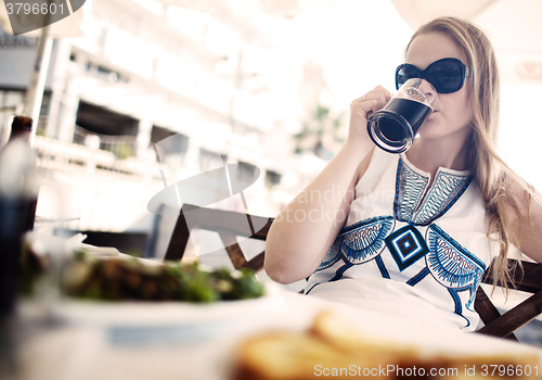 Image of Woman enjoying a dark beer with her meal