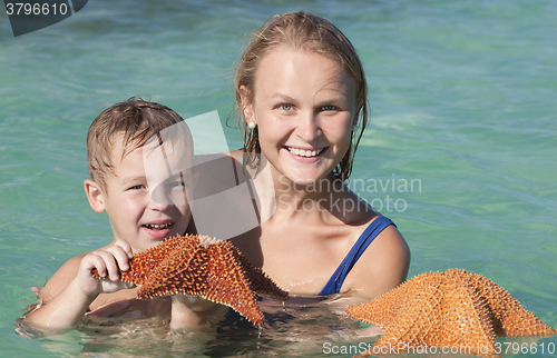 Image of Mother and son in sea holding starfish