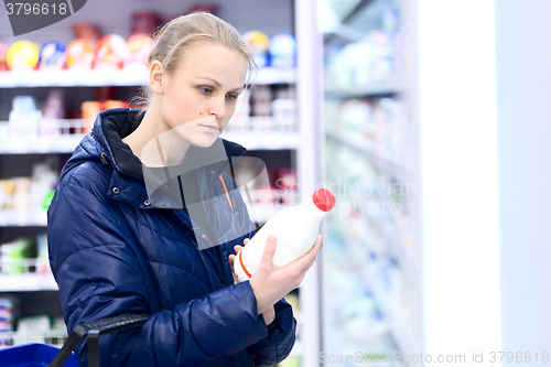 Image of Woman in grocery holding milk