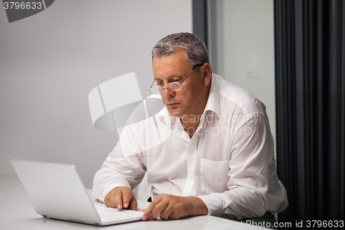 Image of Senior businessman working with laptop in office