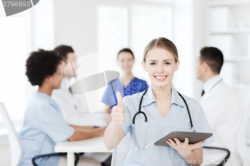 Image of happy doctor with tablet pc over team at clinic