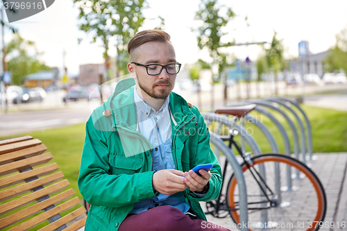 Image of happy young hipster man with smartphone and bike