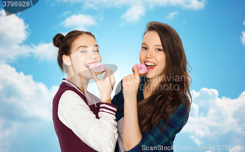 Image of happy pretty teenage girls eating donuts