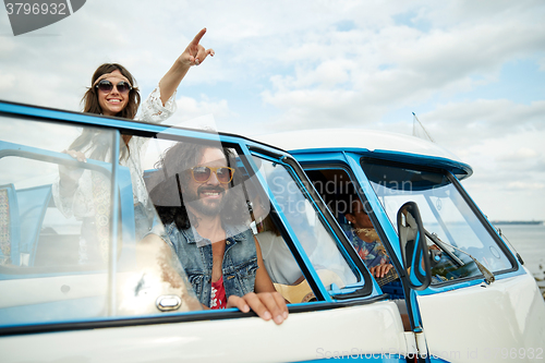 Image of smiling young hippie friends over minivan car