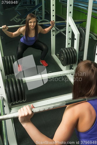 Image of Woman doing shoulder exercise with weight bar