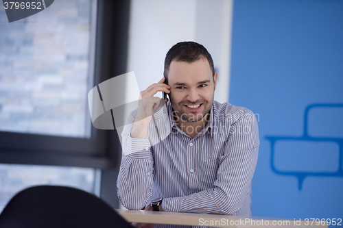 Image of business man talking by phone in office
