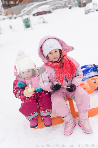 Image of portrait of two little grils sitting together on sledges